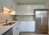 Thumbnail 28 of 48 - A kitchen with white cabinets and a stainless steel refrigerator.