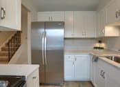 Thumbnail 30 of 48 - A kitchen with a stainless steel refrigerator and white cabinets.