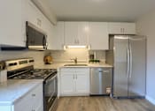 Thumbnail 37 of 48 - A kitchen with white cabinets and a stainless steel refrigerator.