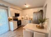 Thumbnail 46 of 48 - A kitchen with a white countertop and wooden chairs.