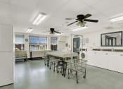 Thumbnail 6 of 18 - a laundry room with a table and chairs and two ceiling fans