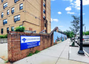 Thumbnail 4 of 18 - a brick wall with a blue sign and a brick building in the background