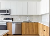 Thumbnail 31 of 73 - A kitchen with a stainless steel dishwasher and wooden cabinets.