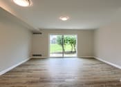 Thumbnail 5 of 48 - A room with wooden flooring and a window leading to a garden.