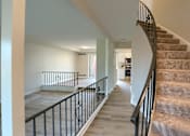 Thumbnail 32 of 48 - A staircase with a black railing and beige carpeted steps.
