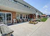 Thumbnail 4 of 15 - a patio with a picnic table and chairs in front of a building
