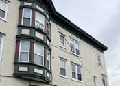 Thumbnail 20 of 23 - A white building with green trim and a black car parked in front.