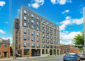 Thumbnail 24 of 73 - A modern multi-story building with a parking lot in front.