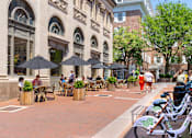 Thumbnail 46 of 67 - a city street with people sitting at tables and umbrellas