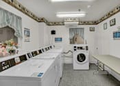 Thumbnail 8 of 16 - a laundry room with washing machines and a table with a vase of flowers
