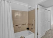 Thumbnail 14 of 16 - a bathroom with tan tiles and a white shower curtain