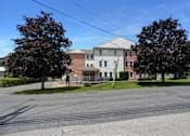 Thumbnail 2 of 16 - Apartments in Three Springs | Three Springs Estates |  a large brick building with a white roof and a street in front of it