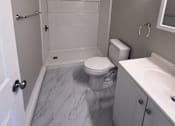 Thumbnail 16 of 23 - A white bathroom with a toilet, sink, and shower.