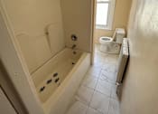 Thumbnail 14 of 23 - A bathroom with a toilet, tub, and window.
