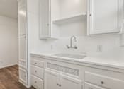 Thumbnail 36 of 40 - A white kitchen with a sink and cabinets.