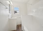 Thumbnail 30 of 40 - A white bathroom with a window and a tub.