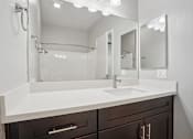 Thumbnail 52 of 53 - A bathroom with a white sink and brown drawers.