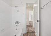Thumbnail 33 of 40 - A white bathroom with a tub and a doorway leading to another room.