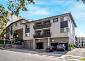 Thumbnail 31 of 49 - A two-story apartment building with a garage and cars parked in front.