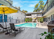 Thumbnail 35 of 49 - A pool area with chairs and a yellow umbrella.