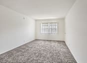 Thumbnail 25 of 40 - A room with a carpeted floor and a window with blinds.