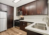 Thumbnail 20 of 40 - A kitchen with brown cabinets and a white sink.