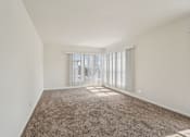 Thumbnail 27 of 40 - A room with a carpeted floor and a window with blinds.