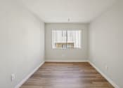 Thumbnail 26 of 48 - A room with wooden floors and a window with blinds.