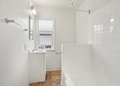 Thumbnail 37 of 40 - A white bathroom with a shower, sink, and mirror.