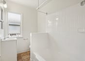 Thumbnail 39 of 40 - A white bathroom with a tub, sink, and window.