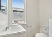 Thumbnail 34 of 40 - A white sink and toilet in a bathroom with a window.