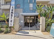 Thumbnail 16 of 53 - A blue building with a sign that says "NOW LEASING" in front of it.