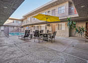 Thumbnail 10 of 41 - A yellow umbrella is on a table outside a building.