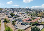 Thumbnail 47 of 51 - A sunny day in a residential area with houses and parked cars.