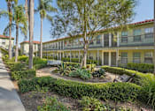 Thumbnail 32 of 51 - A sunny day at a residential complex with a well-maintained garden in the foreground.