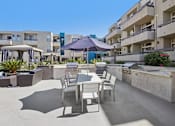 Thumbnail 22 of 53 - A patio with a table and chairs is surrounded by buildings.