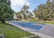 Thumbnail 34 of 51 - A park with a blue basketball court and a metal railing.