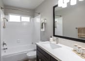 Thumbnail 9 of 11 - A white bathroom with a white tub and sink.