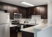 Thumbnail 10 of 11 - A kitchen with dark brown cabinets and a white counter.