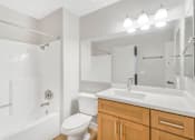 Thumbnail 9 of 30 - A white bathroom with a toilet, sink, and bathtub.