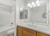 Thumbnail 24 of 30 - A white bathroom with a toilet, sink, and mirror.