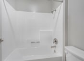 Thumbnail 25 of 30 - A white bathroom with a tub and shower.