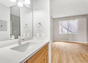 Thumbnail 17 of 30 - A bathroom with a white sink and wooden floors.