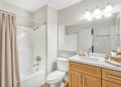 Thumbnail 3 of 30 - A bathroom with a white toilet, a white sink, and a white bathtub.