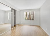 Thumbnail 23 of 30 - A room with a wooden floor and a large mirror on the wall.