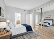 Thumbnail 6 of 30 - A bedroom with a large bed and a mirror on the wall.
