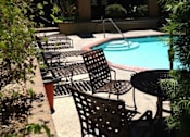 Thumbnail 19 of 37 - A poolside area with chairs and an umbrella.