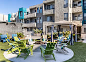 Thumbnail 29 of 54 - a patio with rocking chairs and a fire pit in front of an apartment building