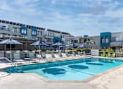 Thumbnail 39 of 54 - a swimming pool with chairs and umbrellas in front of an apartment building