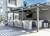 Thumbnail 35 of 54 - a patio with a bar and chairs and a television